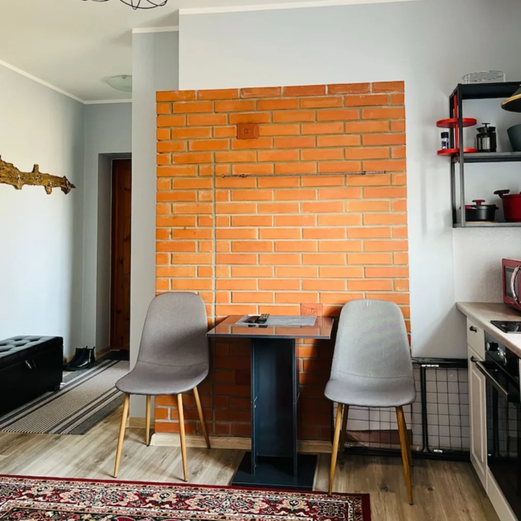 Söögilaud kahe tooliga tellisteseina ees Roomassaare 12 korteris